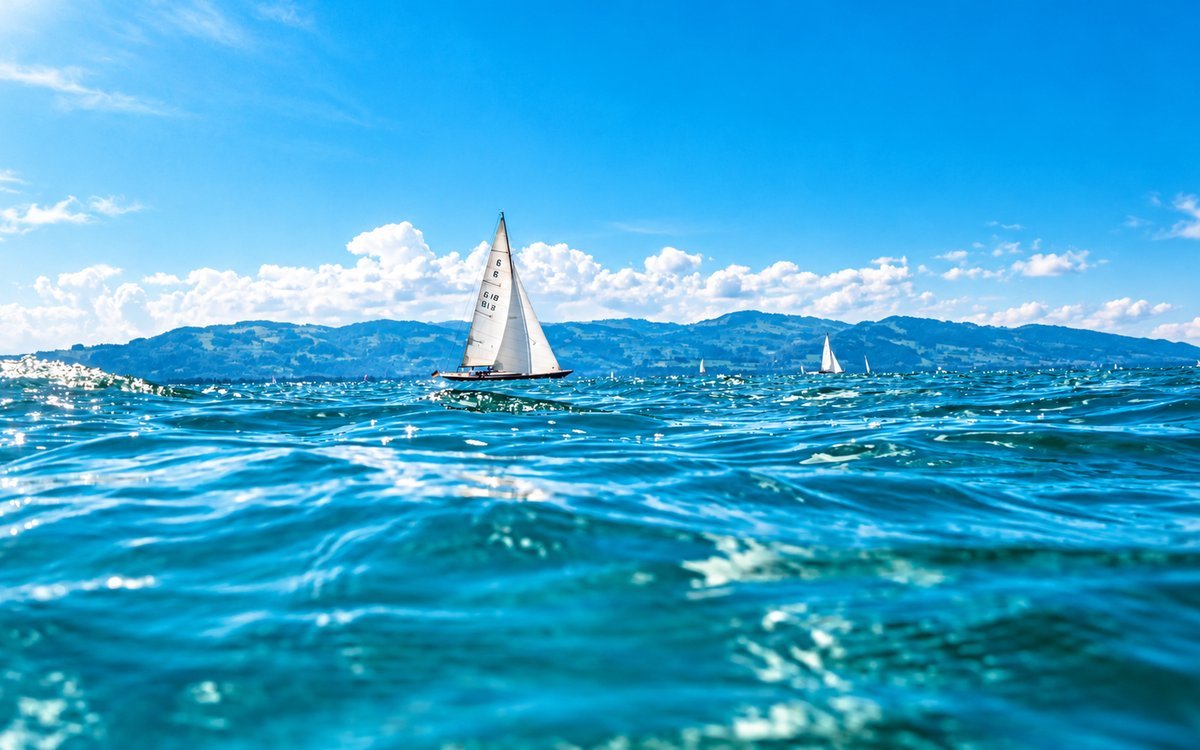Segelboot auf dem Bodensee vor den Hügeln des gegenüberliegenden Ufers
